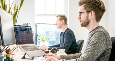 Two men at an office working on their computers